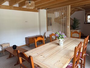 A wooden dining table with chairs, a vase of flowers, and a small wooden cabinet.