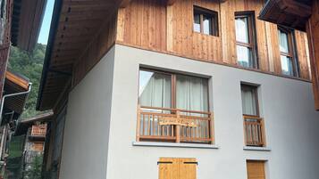 A two-story building with wooden balconies, a door, and a window.