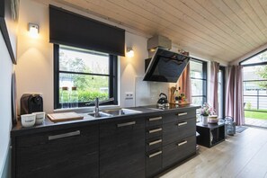 Eine moderne Küche mit einer großen Kochinsel, eingebauten Geräten und Blick ins Freie.