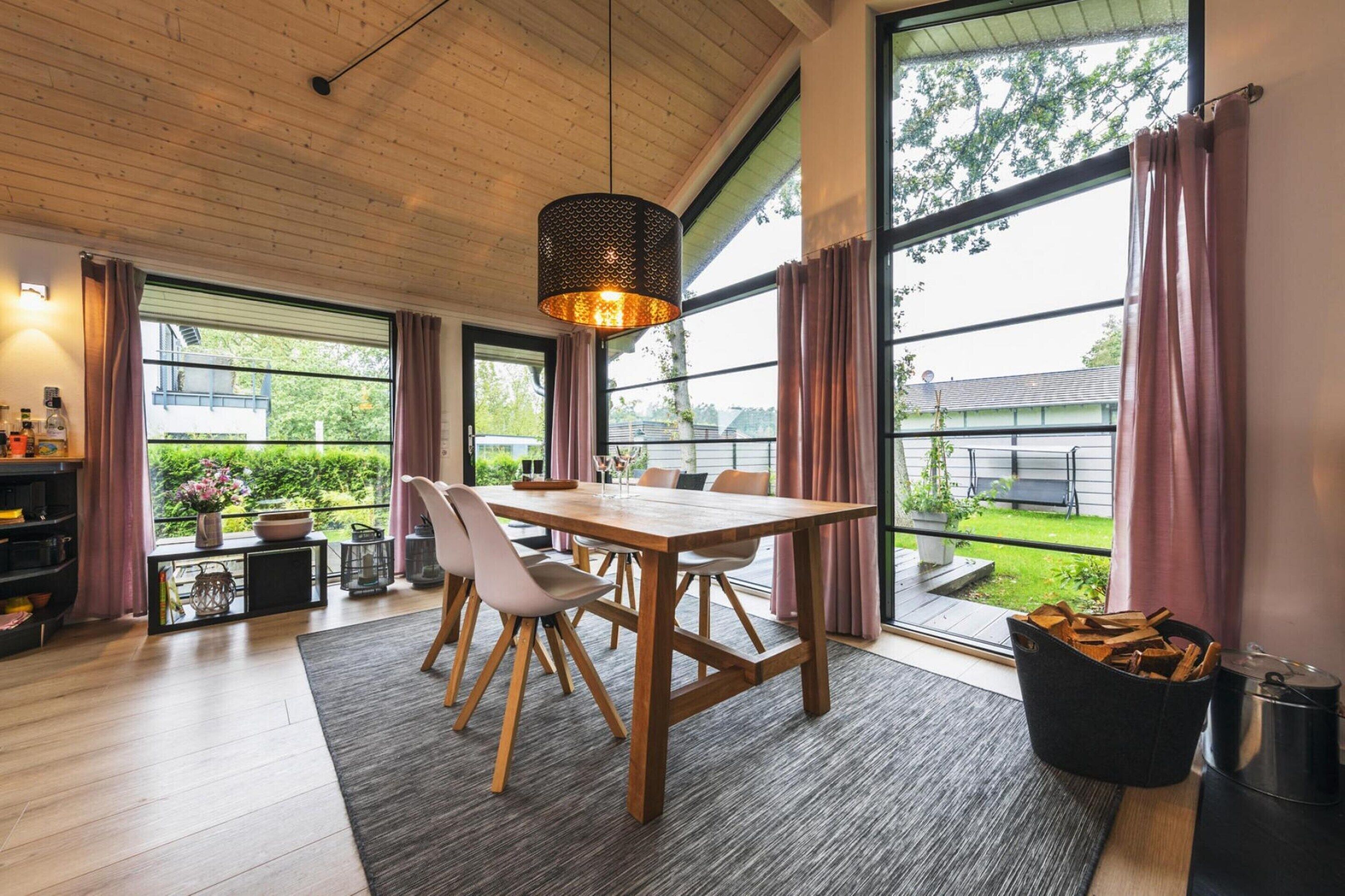 Un comedor moderno con una mesa de madera, sillas y una lámpara colgante.
