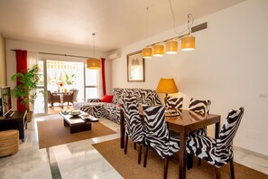 Ein modernes Wohnzimmer mit einer Couch, Sesseln mit ZEBRA-MUSTER, einem Esstisch und einer Lampe.