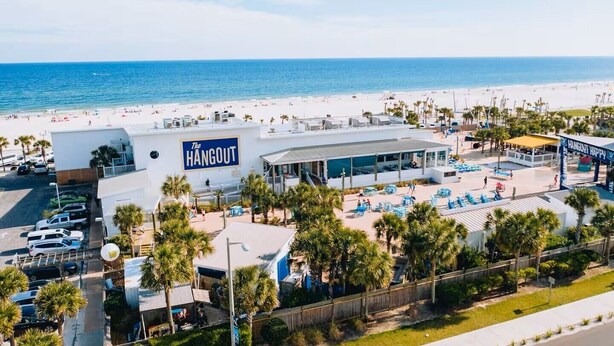 Ein Hotel mit Poolbereich und Blick auf den Strand, mit einem Schild, das 'The Hangout' zeigt.