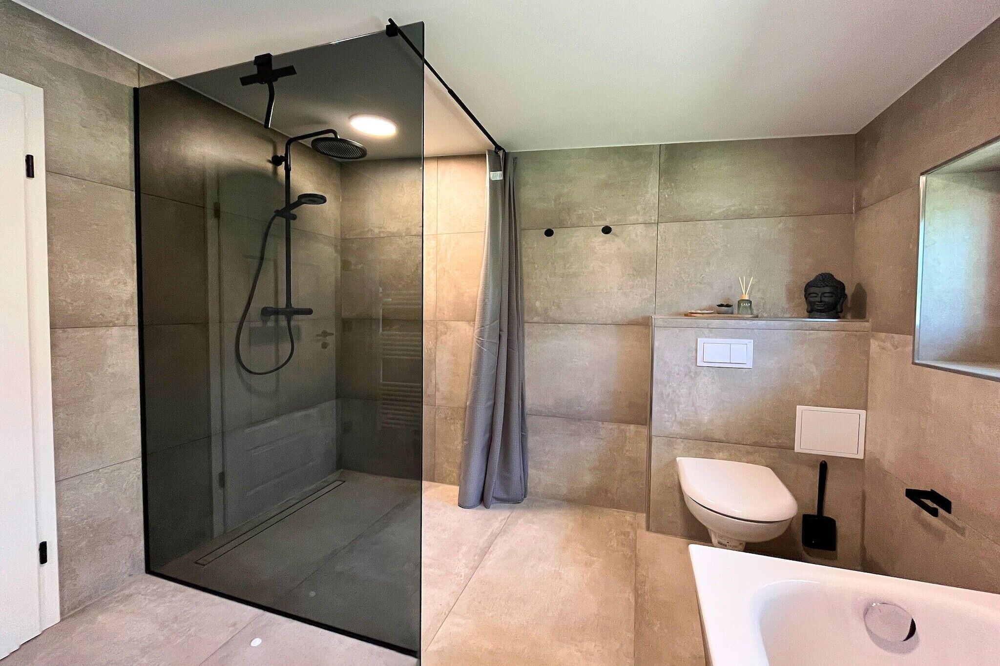 Un baño moderno con ducha envuelta en vidrio, inodoro y bañera.