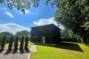 A modern two-story building with a flat roof, a visible entrance, and a paved driveway leading to the entrance. - Ferienhaus Nordwind mit Sauna am Dümmer See (Dümmer)