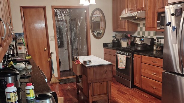 A kitchen with wooden cabinets, a stainless steel refrigerator, a microwave, and a stove. - Charming 1-bedroom available in the house  Burlington perfect for a cozy getaway (Burlington)