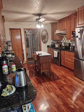 A kitchen with wooden cabinets, a stainless steel refrigerator, a microwave, and a stove.