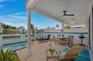 Ein überdachter Außenbereich mit Pool, Liegestühlen, Tisch und Stühlen.