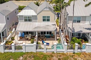 A two-story house with a covered patio, a swimming pool, and a fenced backyard. - Marlin House -  Waterfront Pool Home Near Marina (Marathon)