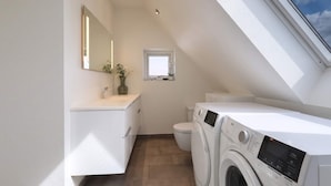 A modern bathroom with a skylight, a washing machine, and a toilet. - 4 Star Holiday Home in Lokken (Lokken)