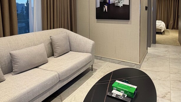 A modern living room with a sofa, a coffee table, and a wall-mounted TV. - 309 Tara-jre 2bedroom at Jabal Al Lweibdeh (Amman)