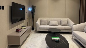A modern living room with a flat-screen TV, a sofa, a coffee table, and a wall-mounted air conditioner. - 309 Tara-jre 2bedroom at Jabal Al Lweibdeh (Amman)