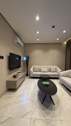 A modern living room with a flat-screen TV, a sofa, a coffee table, and a wall-mounted air conditioner. - 309 Tara-jre 2bedroom at Jabal Al Lweibdeh (Amman)