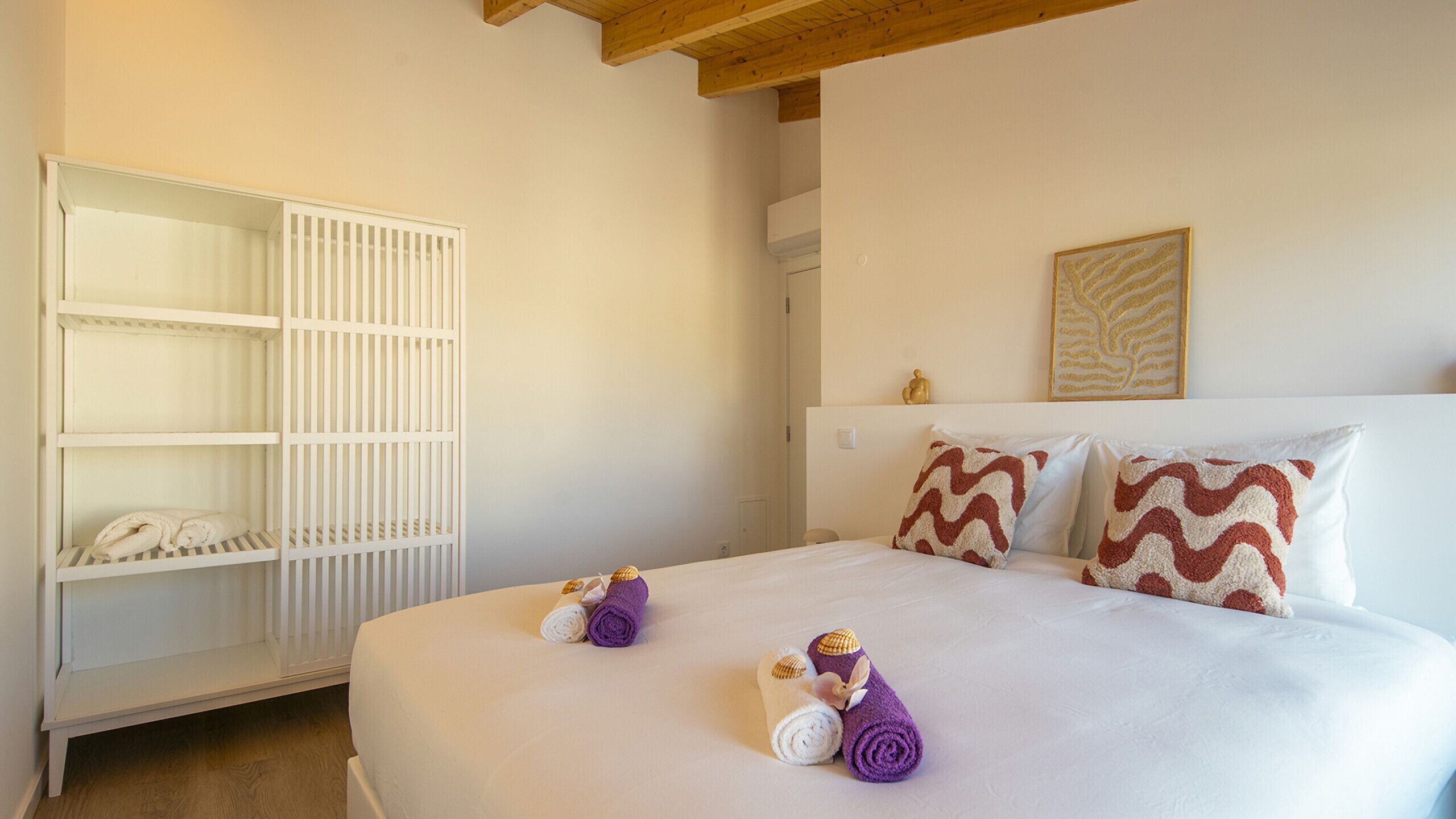 A hotel room with a bed, a wardrobe, and a wall-mounted artwork.
