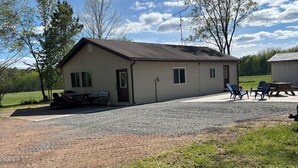 A single-story building with a gravel driveway, a picnic table, and outdoor seating.