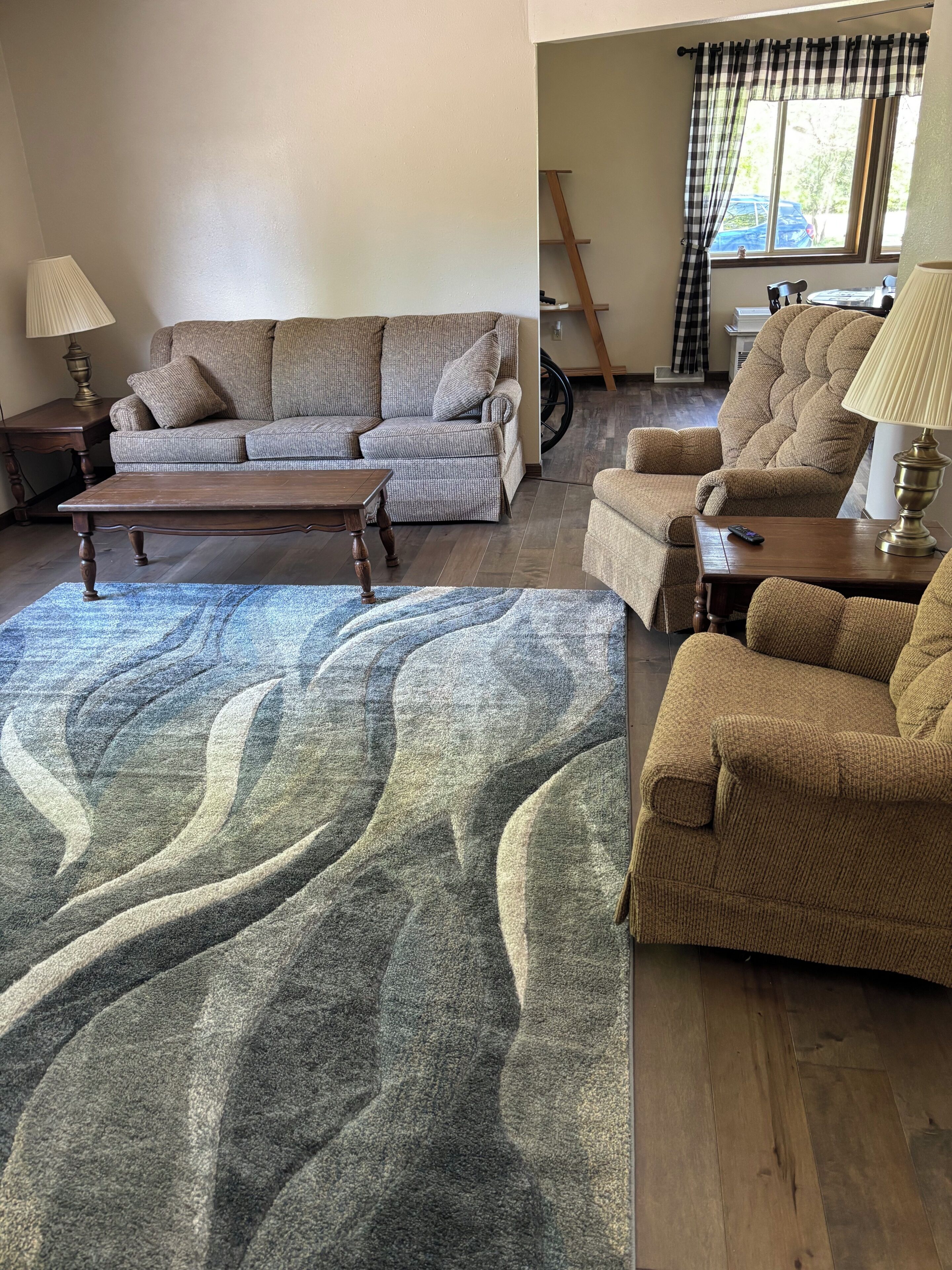 A living room with a sofa, armchairs, a coffee table, and a rug.