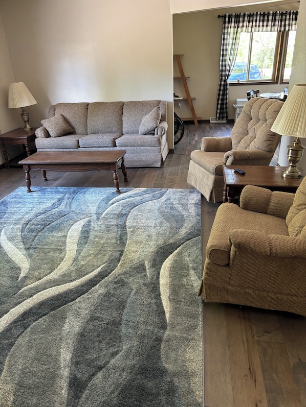 A living room with a sofa, armchairs, a coffee table, and a rug.