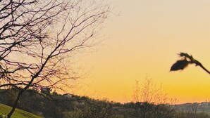 Un entorno tranquilo al aire libre con piscina, terraza de madera y vistas a un paisaje montañoso al atardecer.