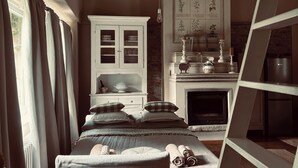 Un dormitorio rústico con una cama de madera, un armario blanco, una chimenea y una escalera.