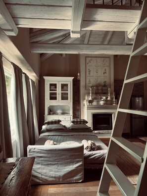Ein rustikales Schlafzimmer mit einem hölzernen Bett, einem weißen Schrank, einem Kamin und einer Leiter.