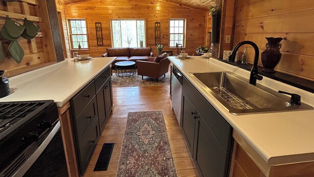 A wooden cabin interior with a kitchen, dining area, and living room.