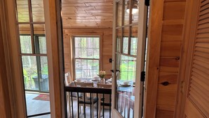 A wooden interior with a dining area, large windows, and a view of the outdoors.