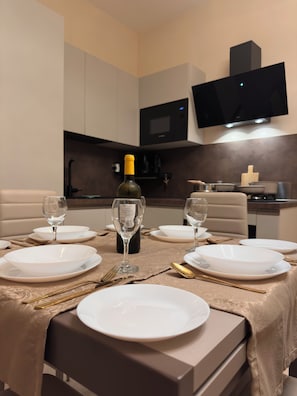 A dining table set with white plates, gold cutlery, and a bottle of wine. - A Dolce Casa Romana Lux | Jacuzzi - Metro A 2 min (Roma)