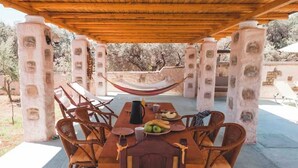 A covered outdoor dining area with a wooden table, wicker chairs, and a hammock. - Unique Villa Pietra: Priv. Pool Oasis, Top Beaches (ΡΟΔΟΣ)