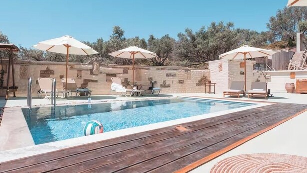 A swimming pool with lounge chairs and umbrellas, surrounded by stone walls and trees. - Unique Villa Pietra: Priv. Pool Oasis, Top Beaches (ΡΟΔΟΣ)