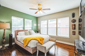 Ein Schlafzimmer mit Bett, Nachttisch, Lampe und Deckenventilator.