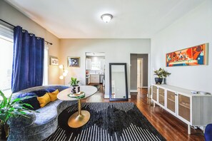 Ein modernes Wohnzimmer mit Sofa, Couchtisch und Blick zur Küche.