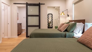 A bedroom with two beds, a sliding door, a mirror, a bedside lamp, and a view of the outside. - Charming 2-bedroom 2-bath house close to Texas State University and the River (San Marcos)
