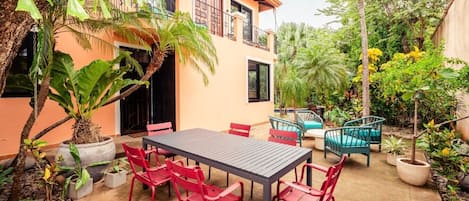 A patio with a table and chairs, surrounded by potted plants and a building.
