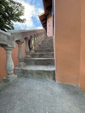 Een betonnen trap met balustrades die naar een gebouw leidt, met een perzikkleurige muur.