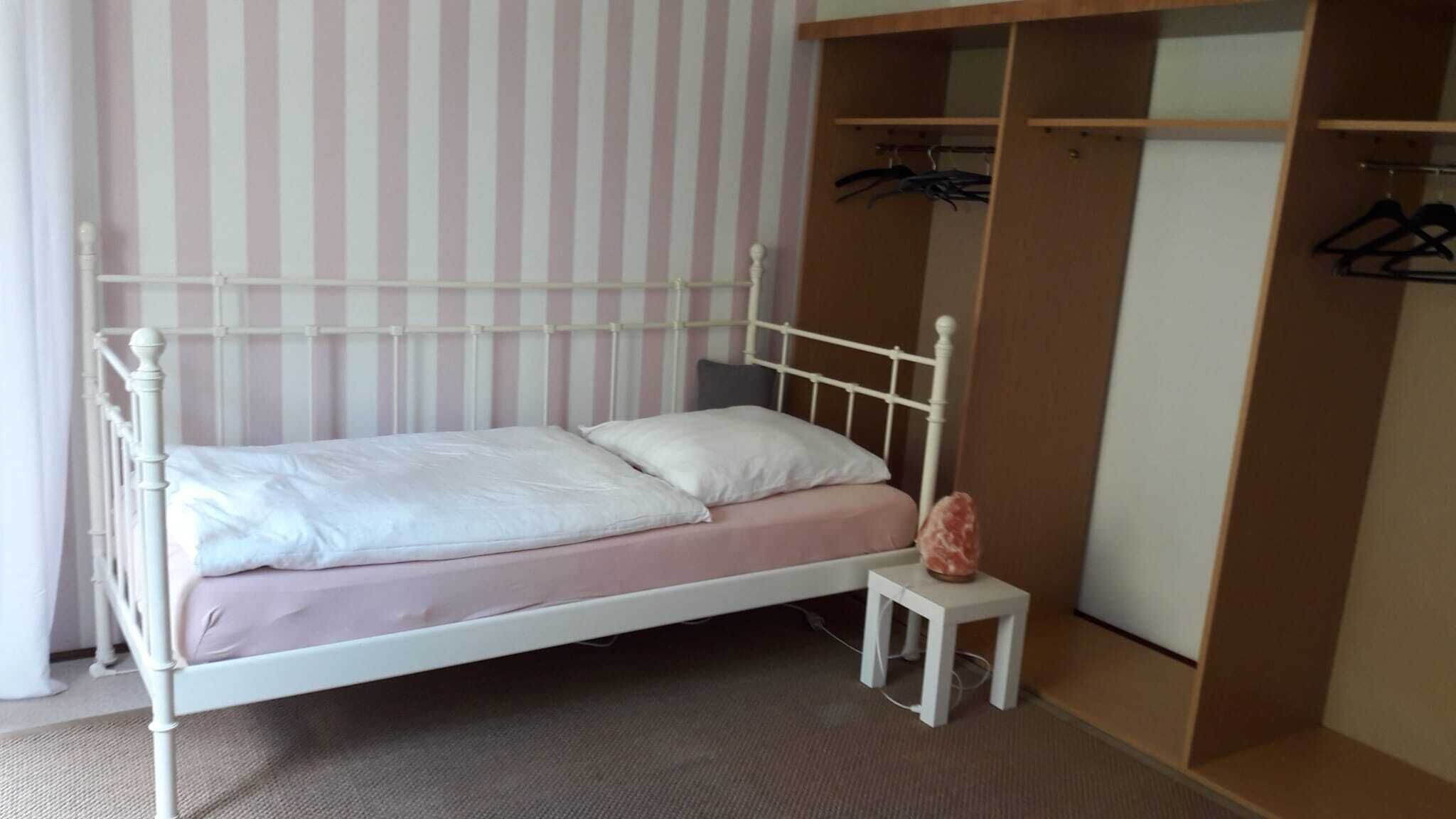 A single bed with a headboard, a bedside table, and a wardrobe with hanging space.