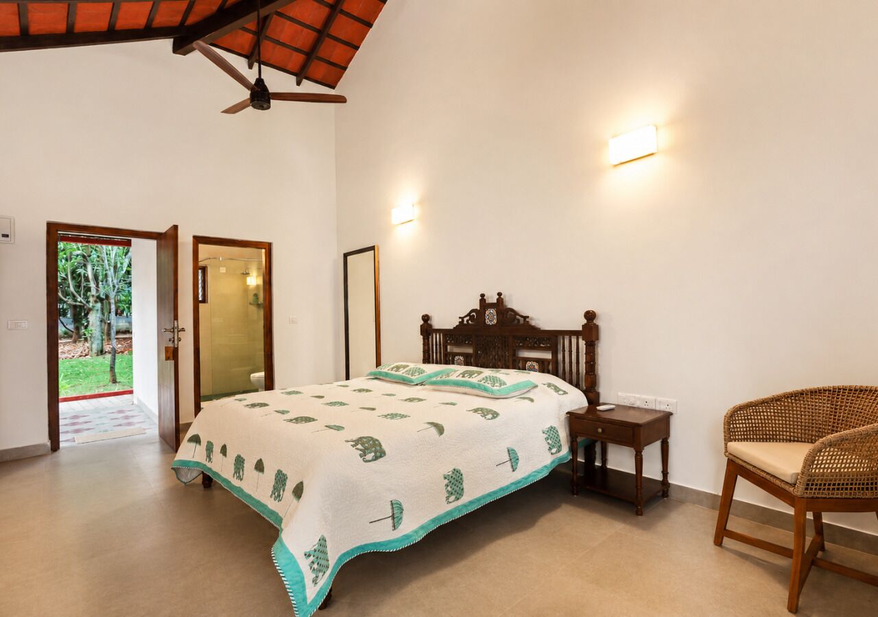 A bedroom with a bed, a desk, a chair, and a ceiling fan.
