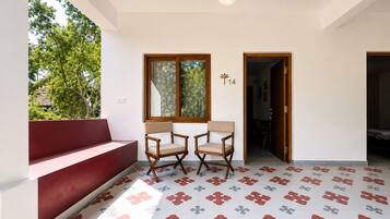 A room with a red bench, two wooden chairs, a table, and patterned floor tiles.