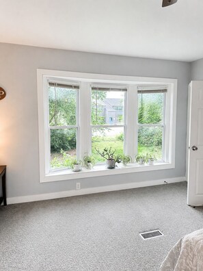 Ein Zimmer mit großem Fenster, einer Tür und einem Heizkörper.