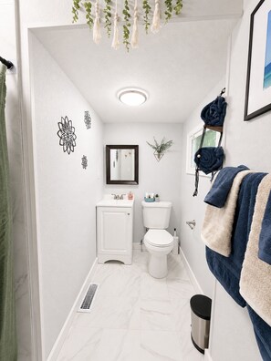 Un bagno con il water, un lavandino, uno specchio e un porta asciugamani.