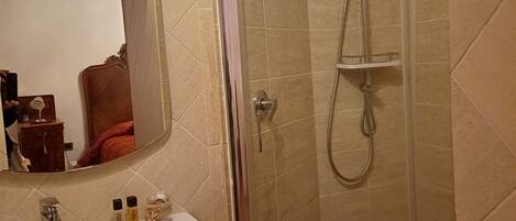 Une salle de bain avec un lavabo, un miroir, une douche et des murs carrelés.