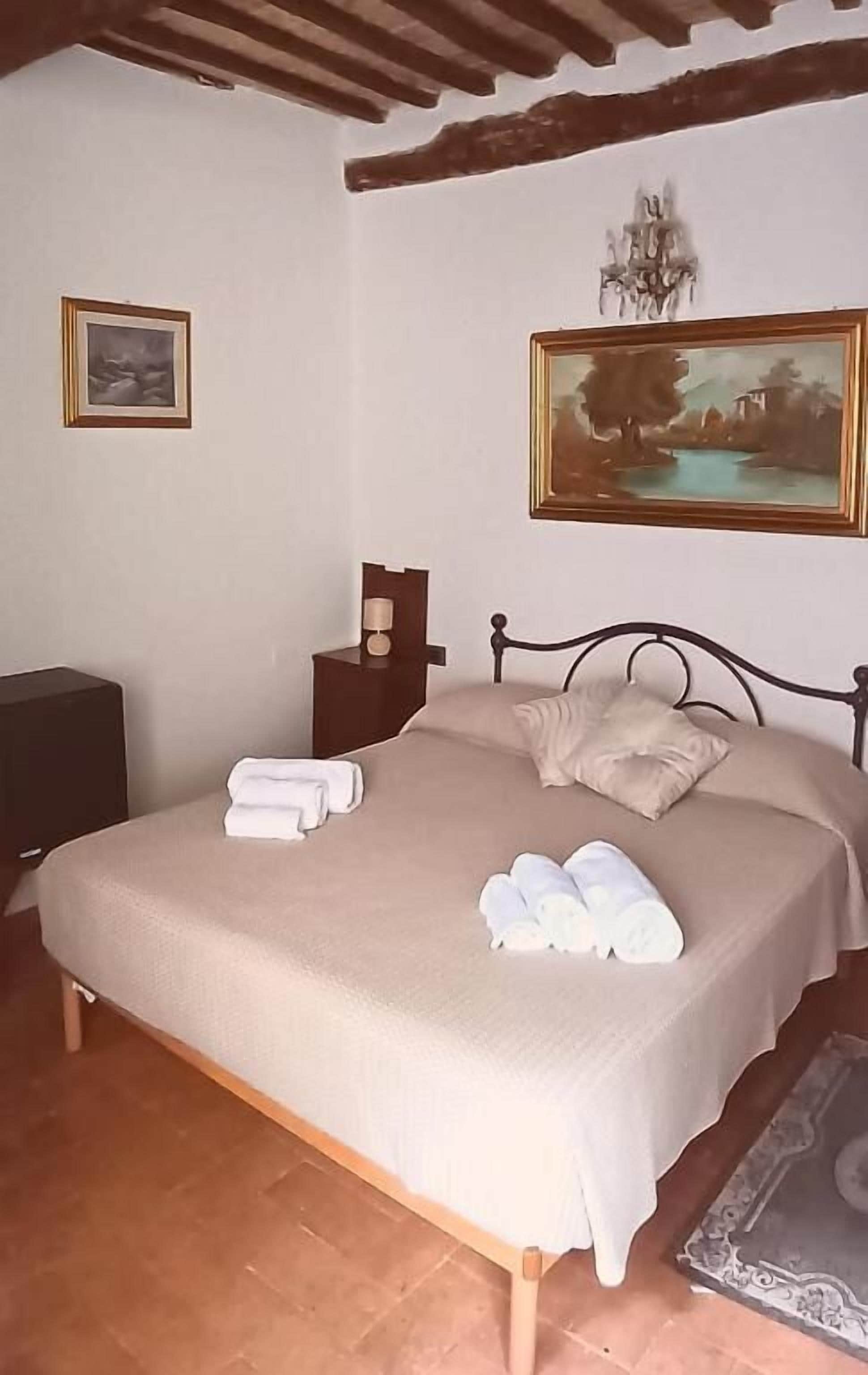 Una camera da letto con un letto, un comodino, una lampada e un quadro appeso al muro.
