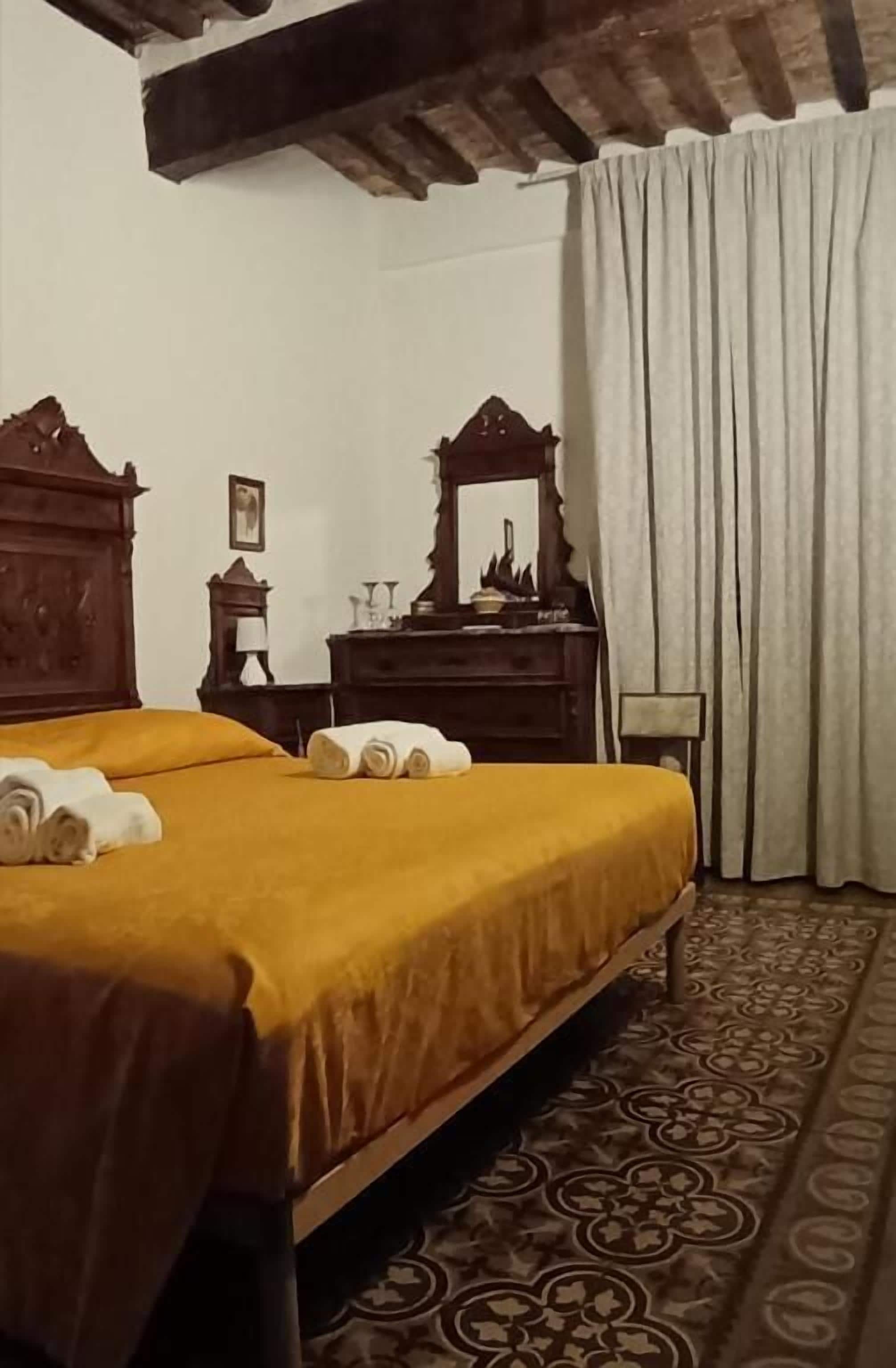 A room with a bed, a wooden dresser, a mirror, and a patterned carpet.