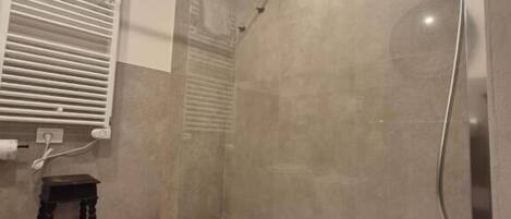 A shower area with a glass door, a small stool, and a patterned floor.