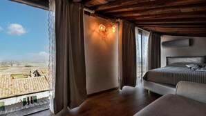 Un dormitorio con cama, vista a un pueblo a través de una ventana y techo de madera.