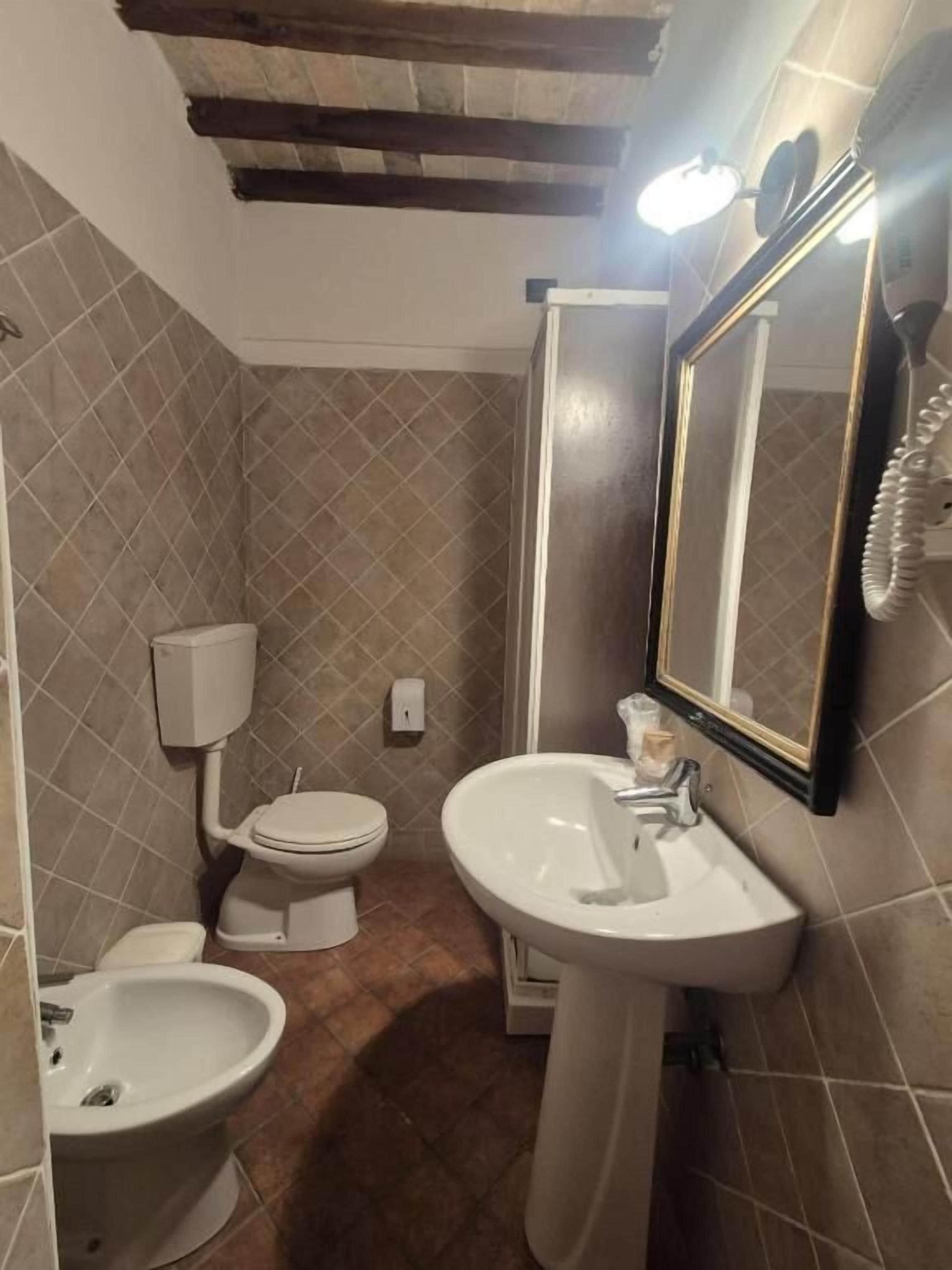 Een badkamer met toilet, bidet, wastafel en spiegel.