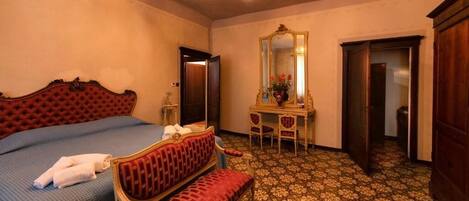 Une chambre d’hôtel comprenant un lit, une banquette, un bureau avec un miroir et une armoire.