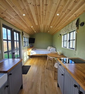 A compact room with a bed, a small table, a TV, and a window.