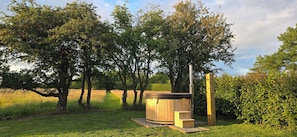 A hot tub in a grassy area surrounded by trees.