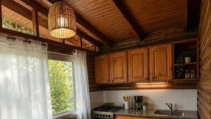 Ein rustikales Holzhaus-Interieur mit Esstisch, Stühlen, einem Herd und Holzschränken.