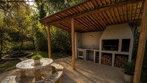 Ein überdachter Außenbereich mit einem Mosaik-Tisch, einem Grill und einem Stauerschrank.