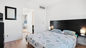 A bedroom with a bed, bedside lamps, a mirror, and a door leading to a bathroom. - Riviera Retreat in Grasse (Grasse)